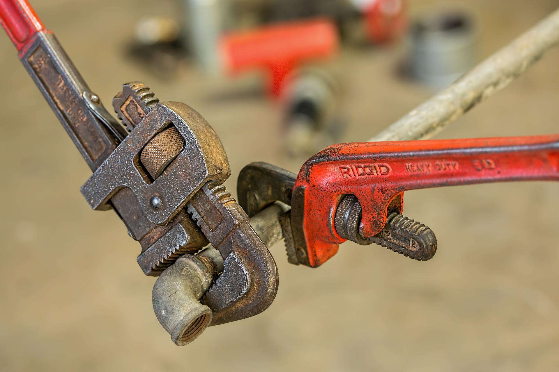 Close-up photograph of two wonderfully-worn wrenches clamped onto a pipe that’s floating in mid-air